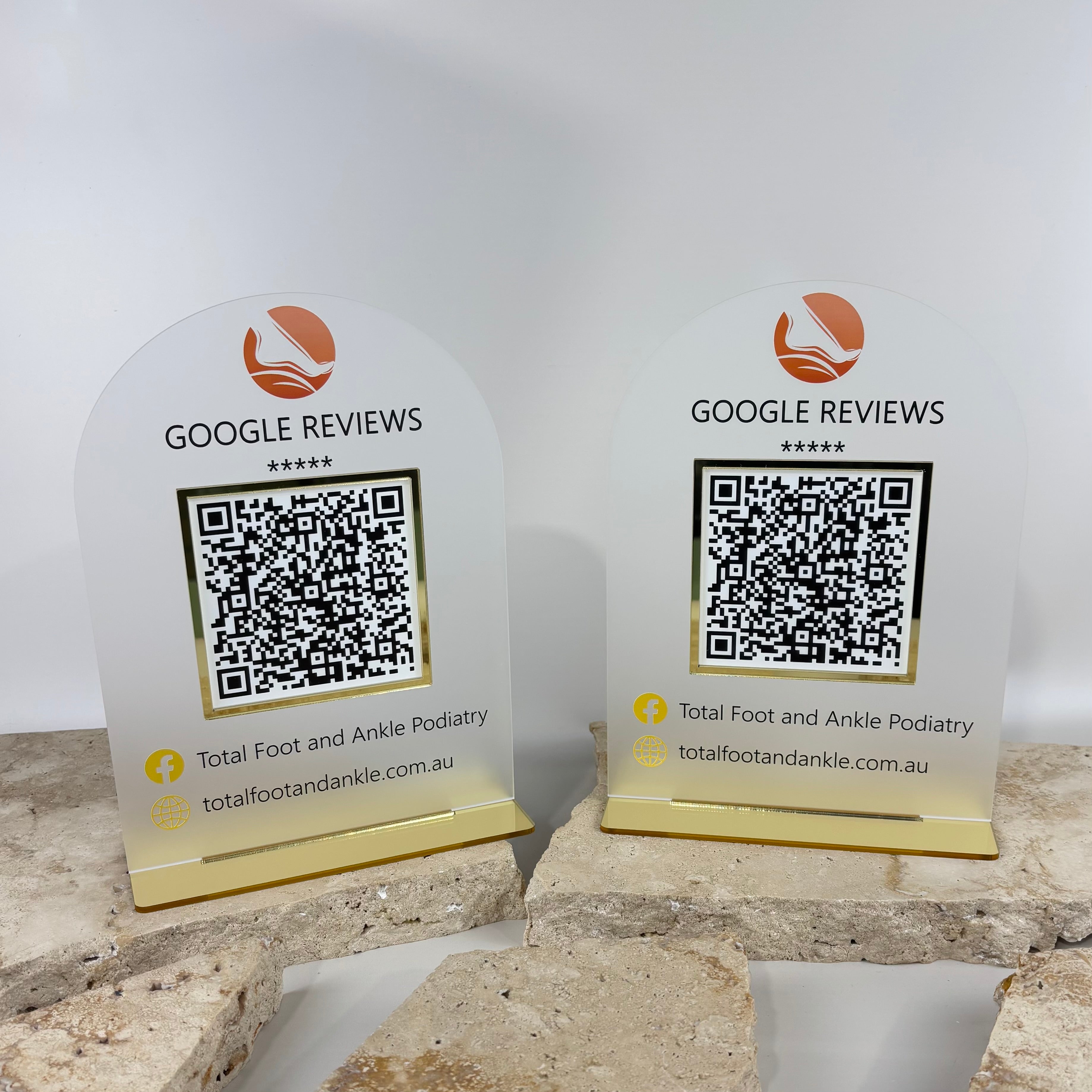 Branded acrylic Google review QR code stands with gold base, countertop display signs designed for clinics and service businesses to encourage customers to leave Google reviews.