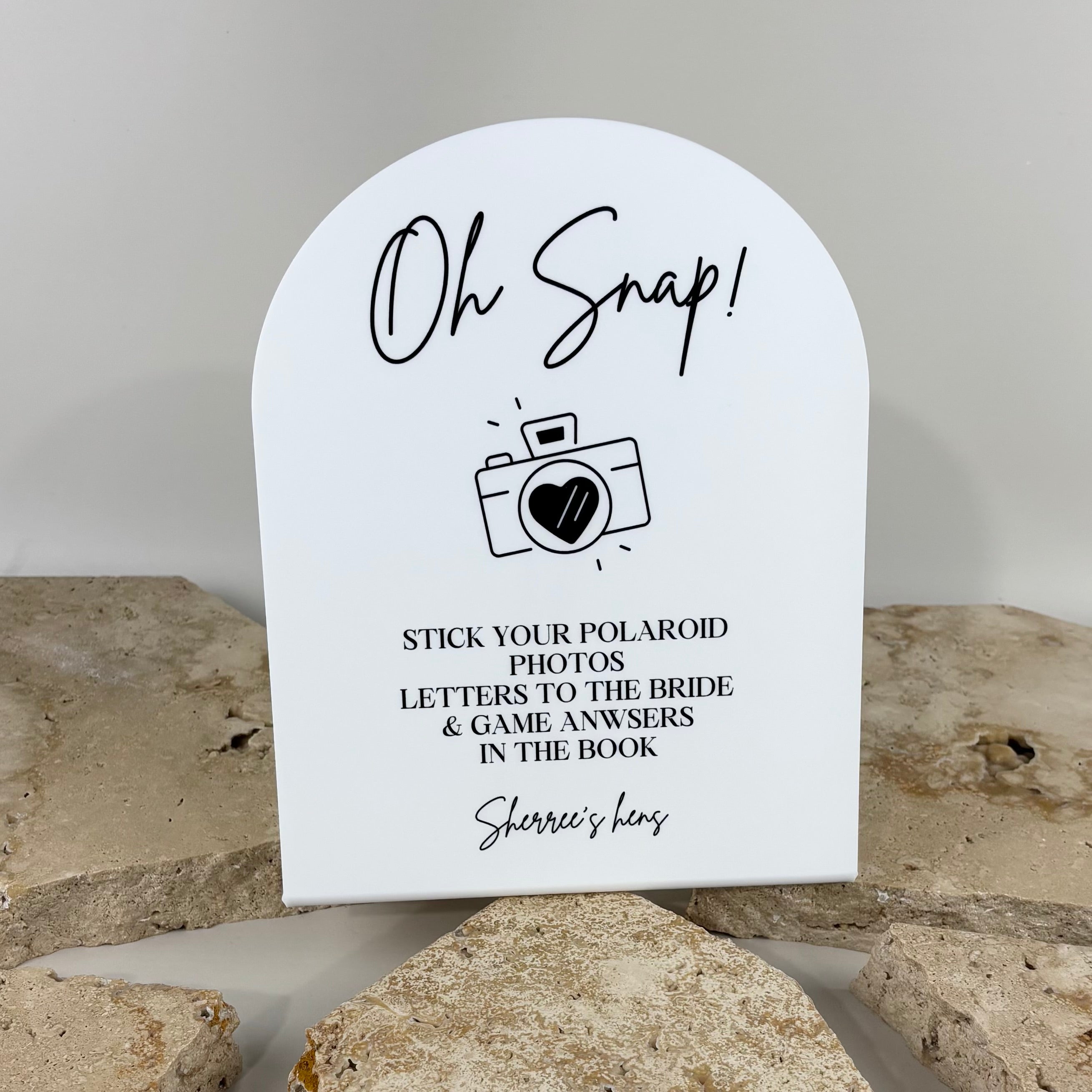 Custom acrylic hens party sign for Polaroid guest books, wedding celebrations and bridal shower events. Personalised arched event sign encouraging guests to add photos, messages and game answers, perfect for memory tables, guest book stations and wedding keepsakes