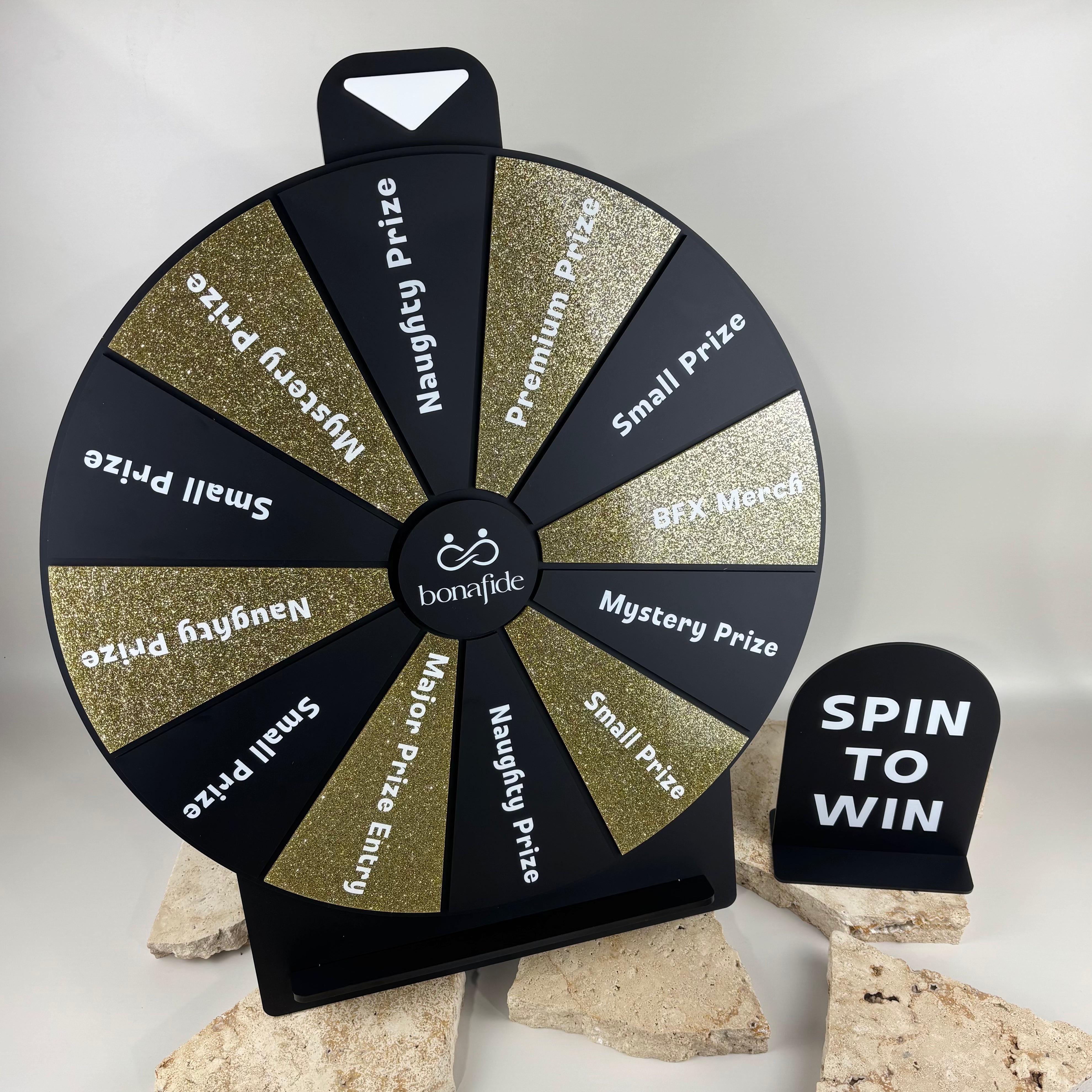 Custom black and gold acrylic spin to win prize wheel with branded logo, glitter prize sections and matching tabletop sign for business promotions, events and giveaways.