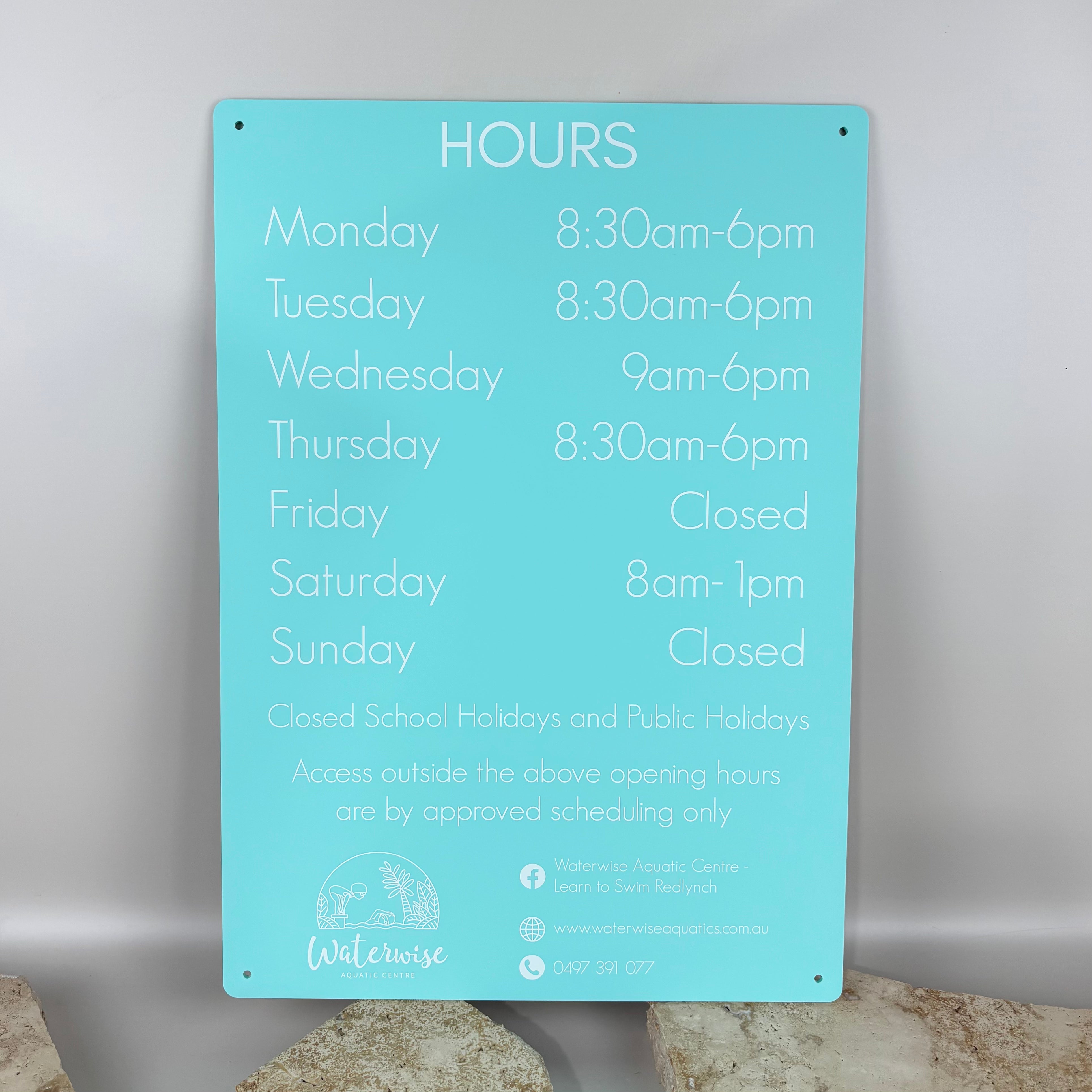 Custom aqua acrylic business hours sign with white UV printed text, wall mounted with rounded corners, displaying weekly opening hours for a swim school and aquatic centre, professional reception signage for commercial premises in Australia.
