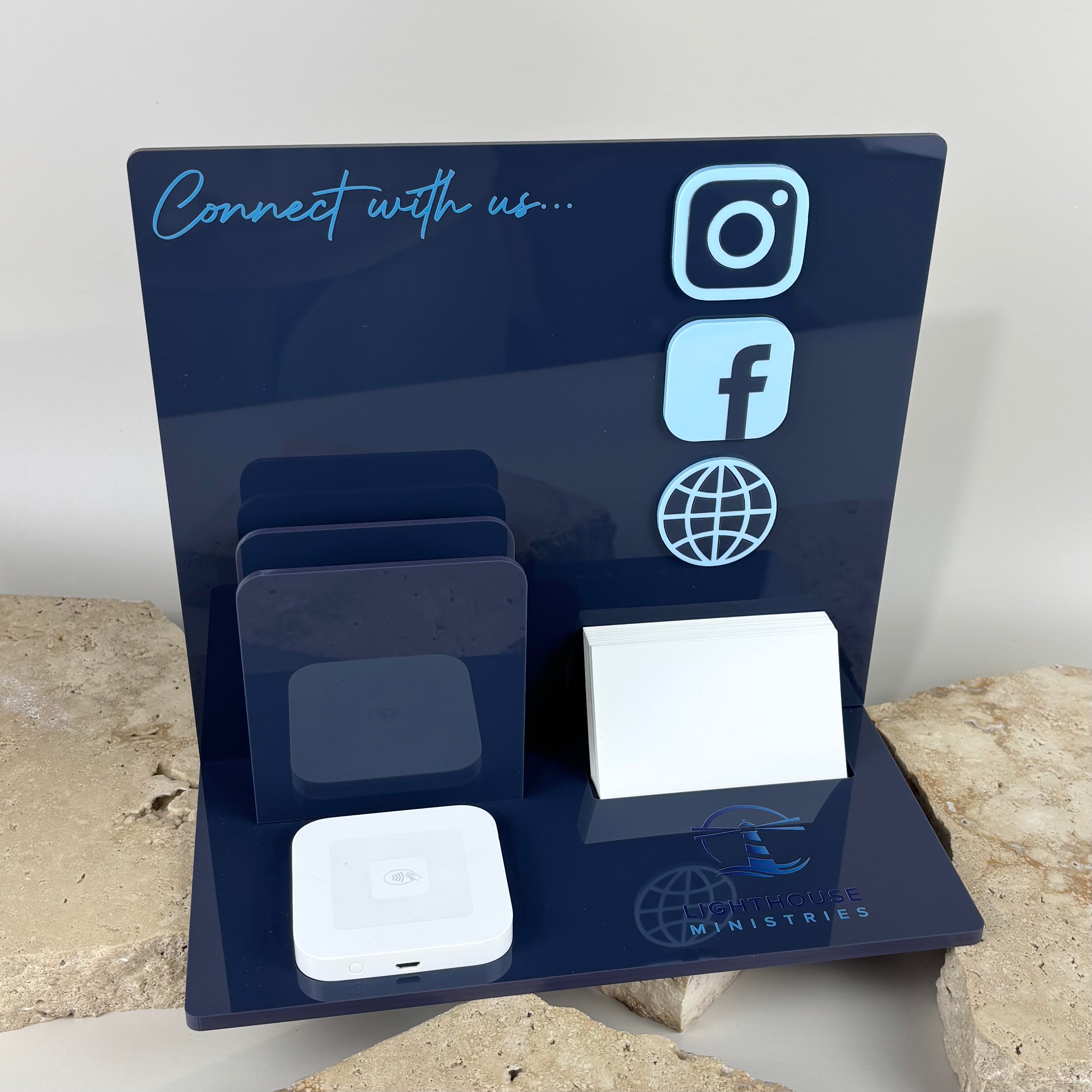 Navy acrylic social media display stand with 3D icons for Instagram, Facebook and website, featuring card holder slots, NFC tap point and business card section, custom branded for Lighthouse Ministries.