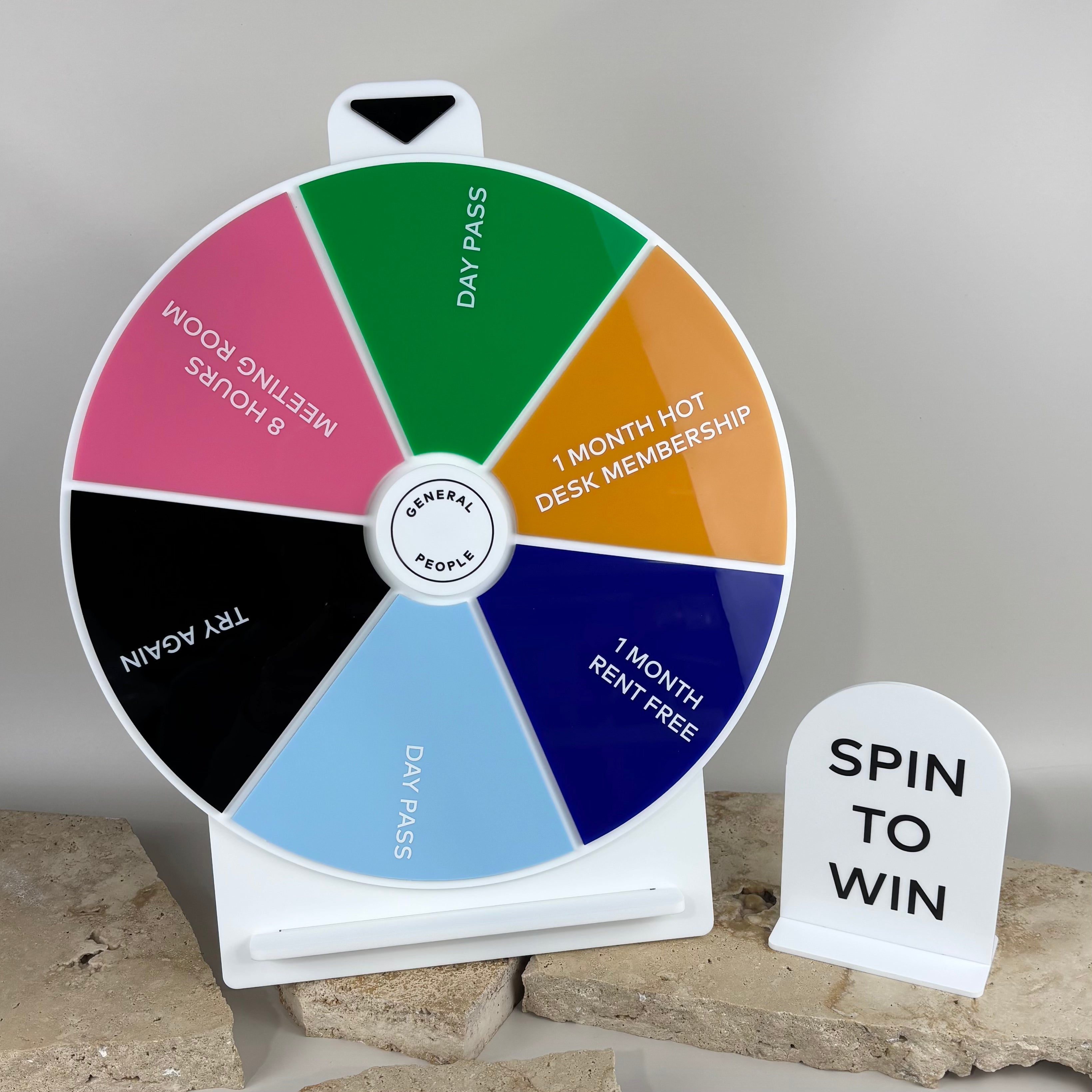 Colourful custom spin the wheel prize display with white base and matching acrylic sign reading ‘Spin to Win’ by Laser Edge Designs, ideal for business promotions, events, and giveaways.