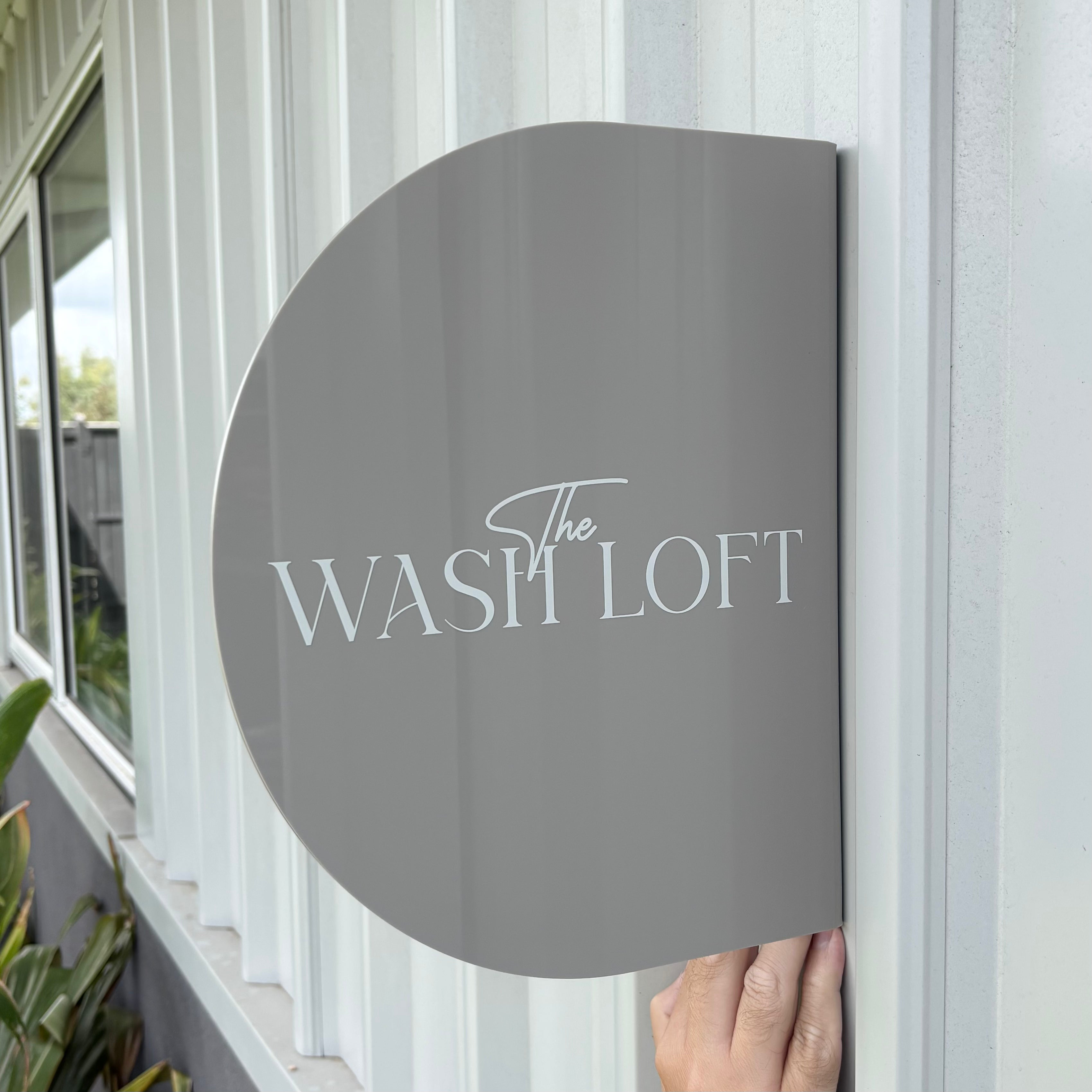 Custom arched acrylic blade sign mounted on exterior wall featuring raised business lettering, modern curved shop front signage for salons, boutiques and retail stores, Australian made business blade sign.