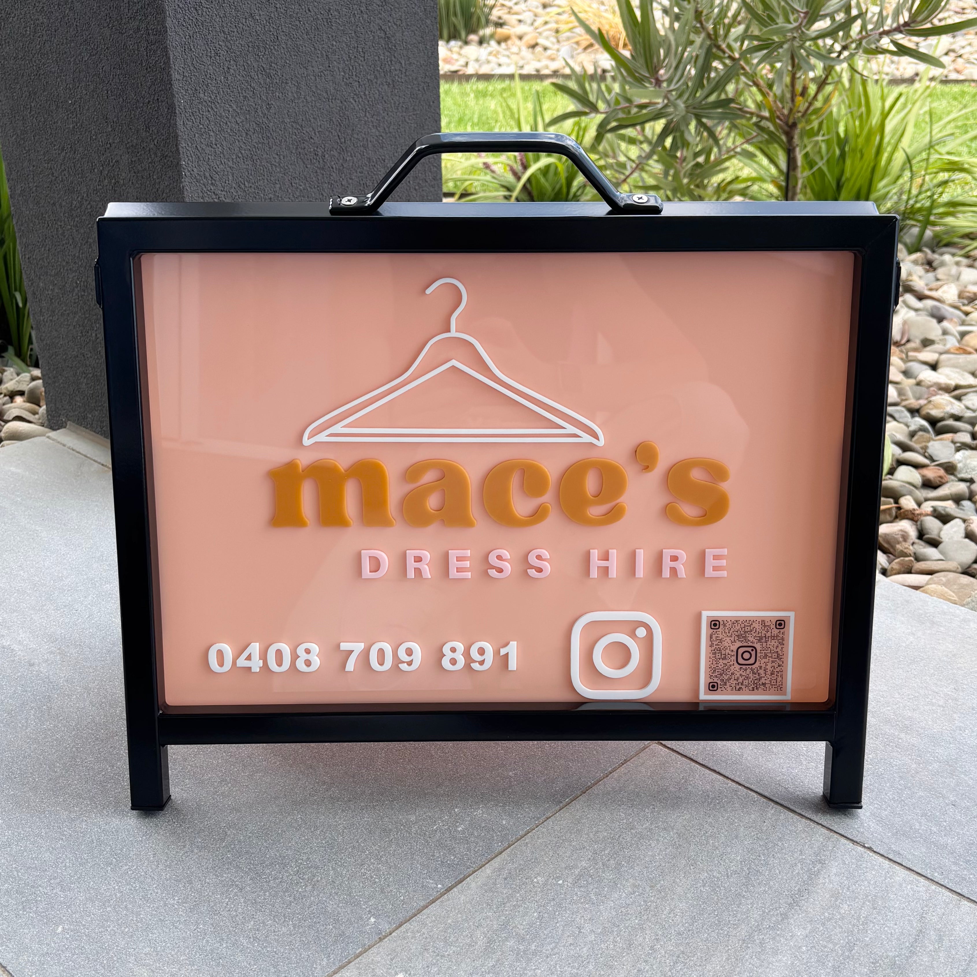 A-frame business sign for Mace’s Dress Hire, featuring blush acrylic panel with raised logo, phone number, Instagram icon and QR code, displayed outdoors as a portable illuminated advertising sign for a fashion hire business.
