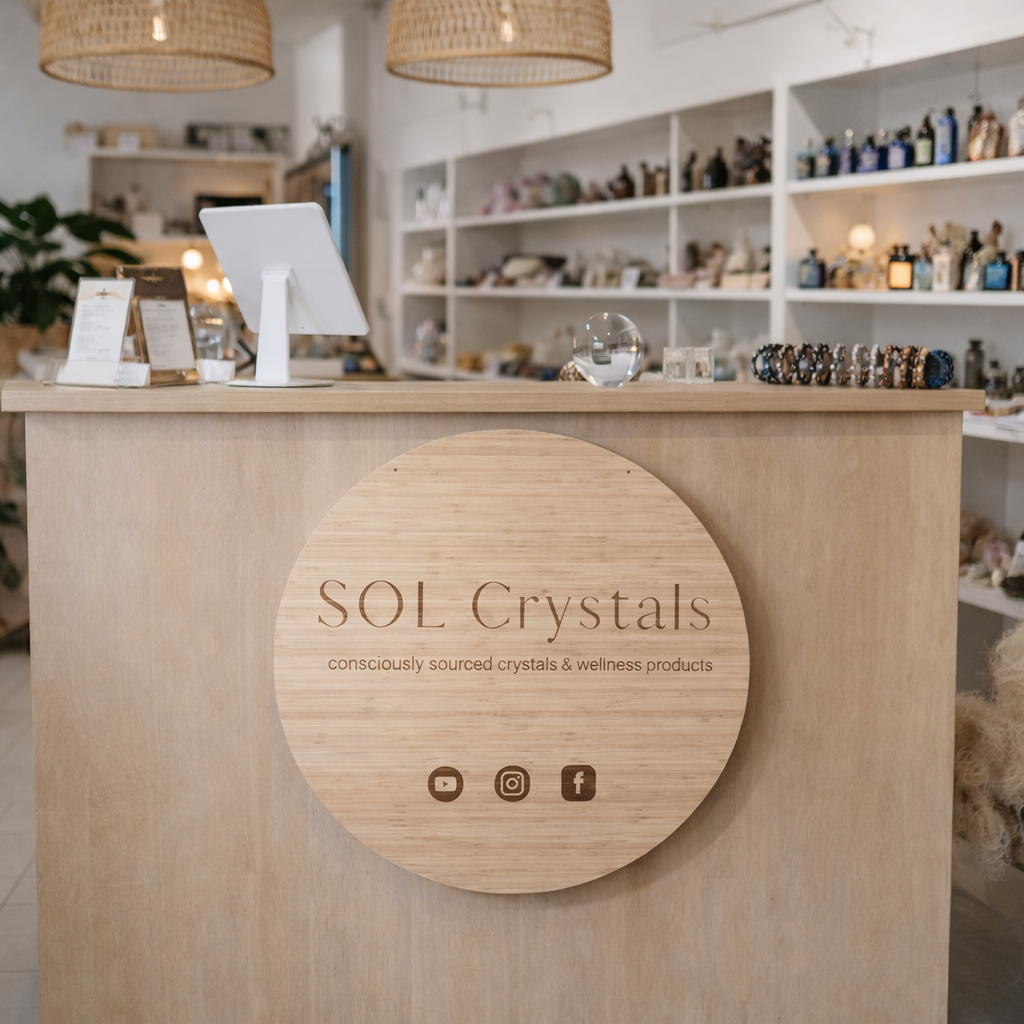 Custom round bamboo business sign centred on reception desk, SOL Crystals retail shop signage, engraved timber logo sign with minimalist branding, crystal and wellness store display Australia, wooden business sign for boutique shop counter