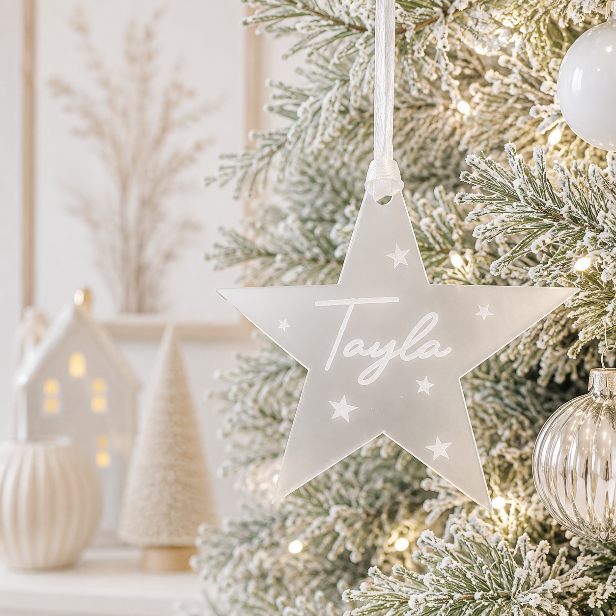 Personalised frosted acrylic star Christmas bauble with custom engraved name and star details, hanging on a modern Christmas tree.