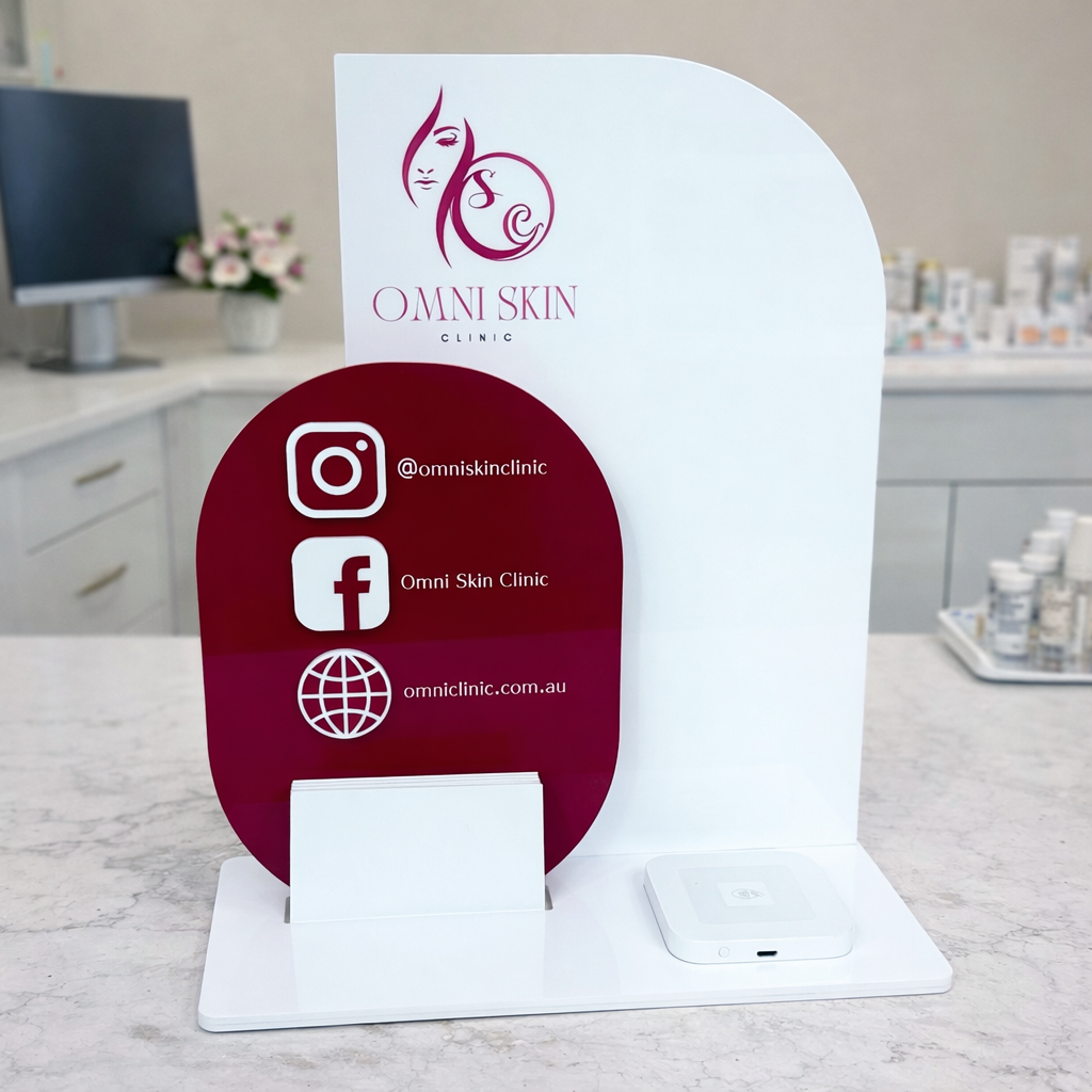 Branded acrylic NFC social media stand for aesthetic clinic on a clinic counter with Omni Skin Clinic logo, Instagram, Facebook and website details
