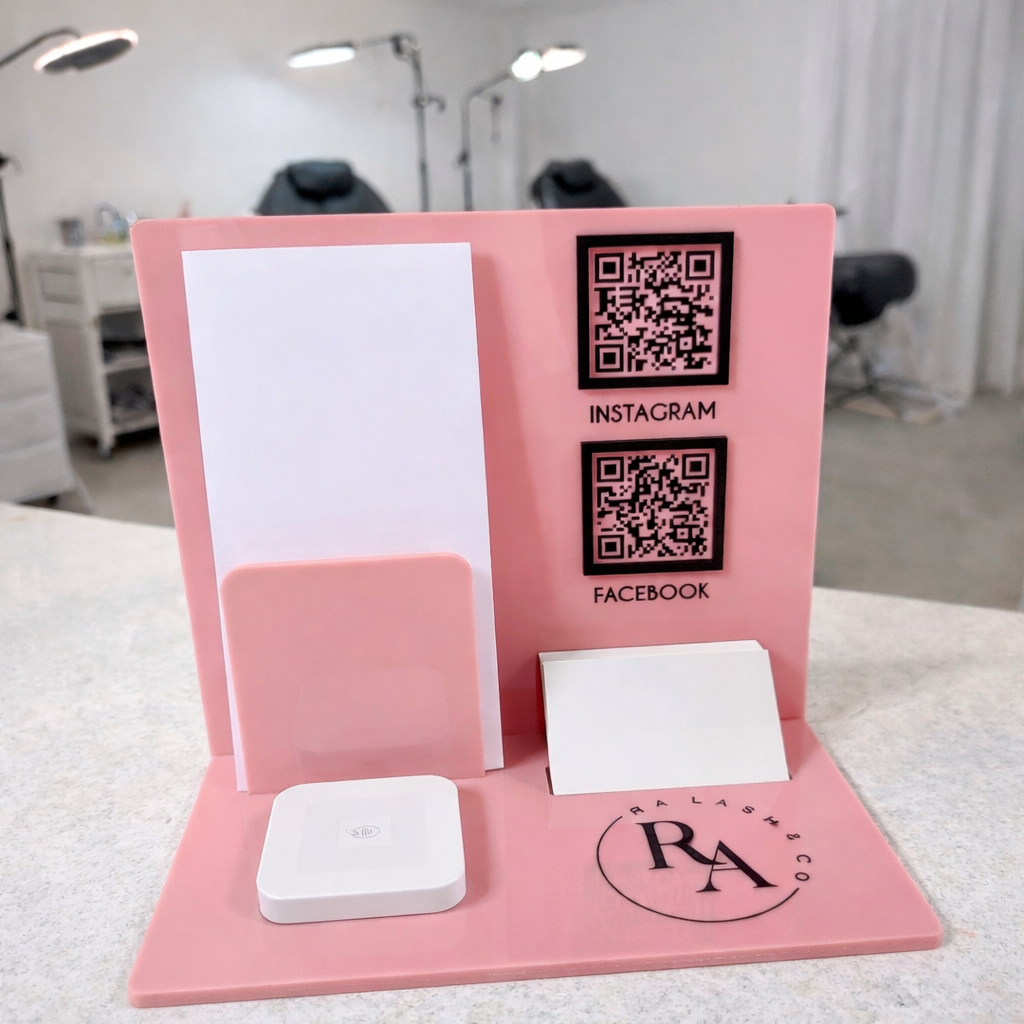 Custom pink acrylic NFC business stand for lash studio displayed on a salon counter, featuring RA Lash & Co branding, Instagram and Facebook QR codes, business card holder and square reader device for tap payments