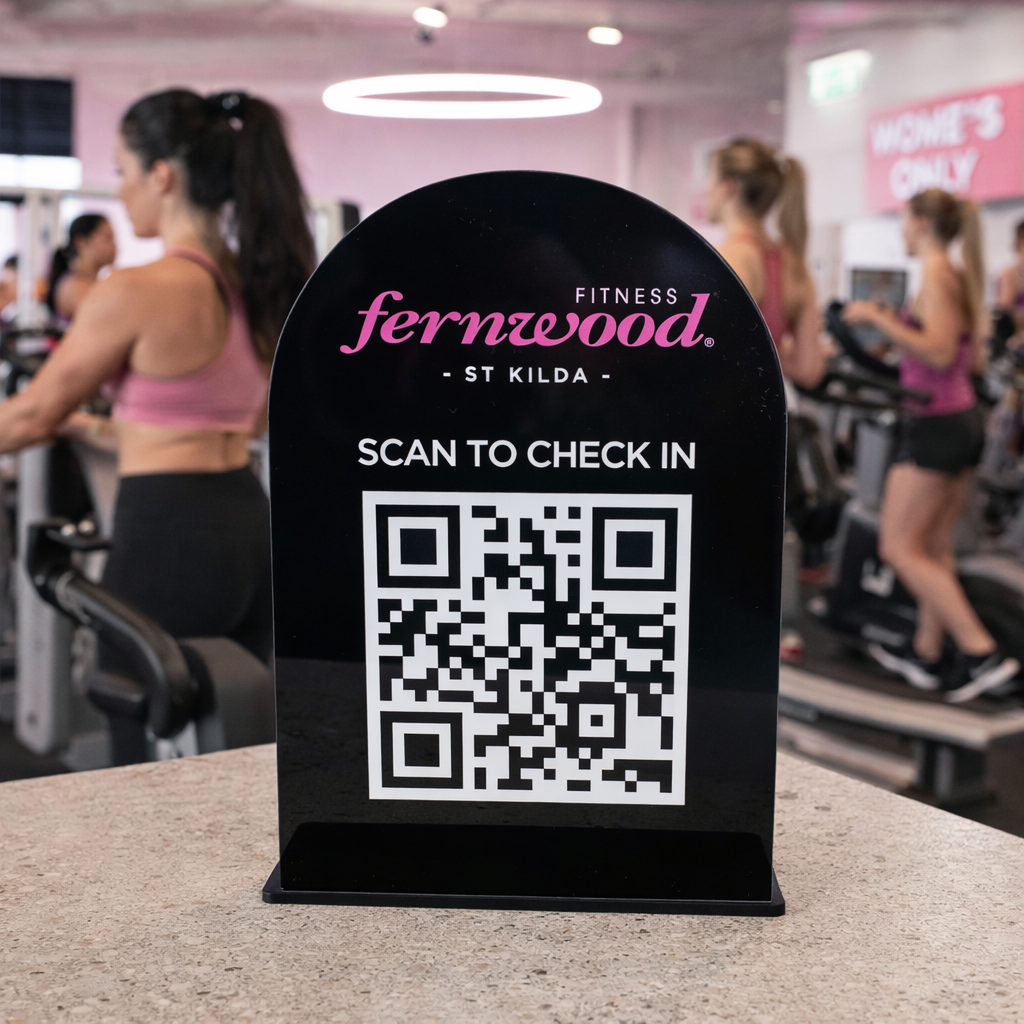 Black acrylic QR code check-in stand displayed at a women’s only gym, custom branded fitness sign for member entry and reception counters.