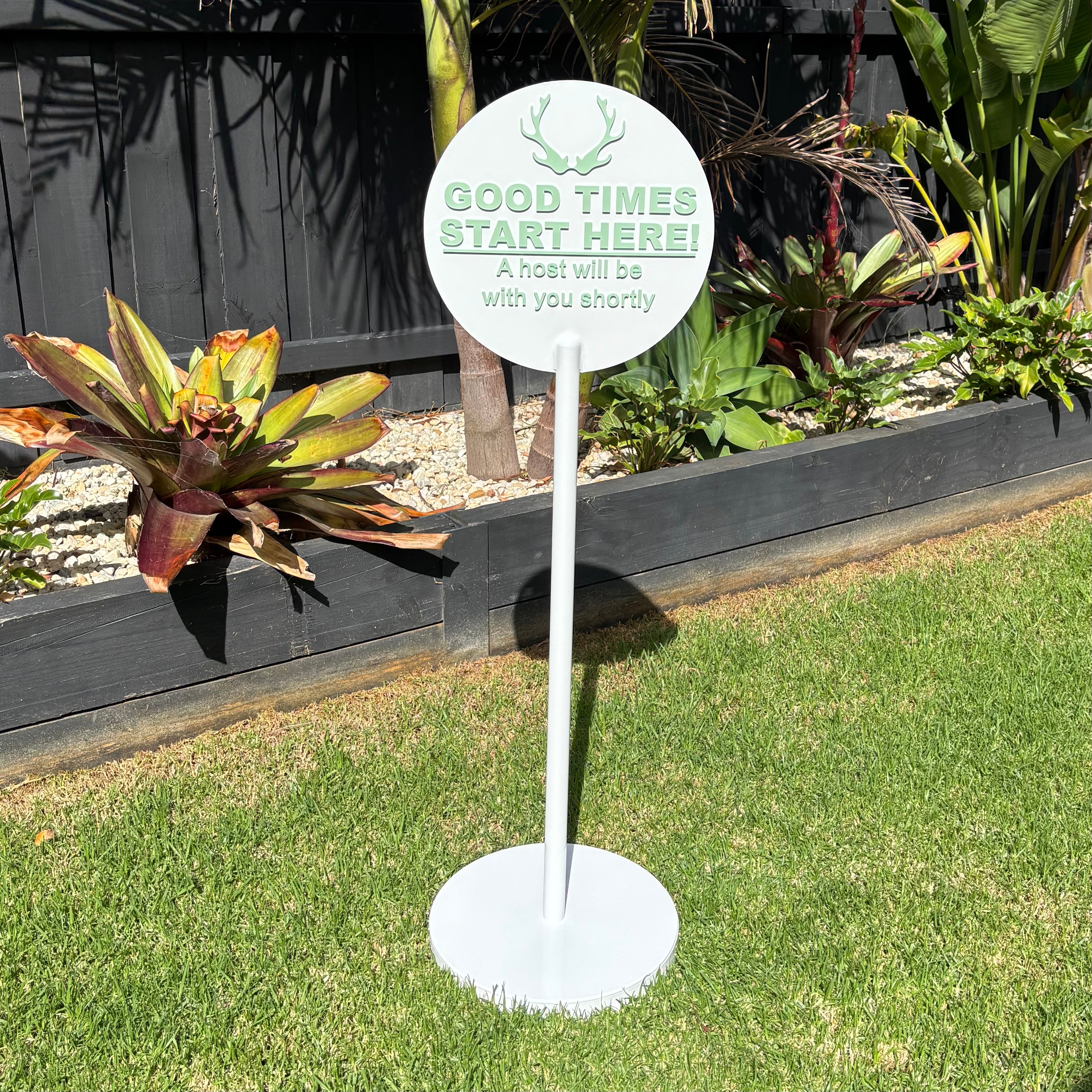 Custom round freestanding sign with stand, white outdoor business sign with raised lettering, “good times start here” welcome sign, modern event or hospitality signage Australia, outdoor acrylic display sign for venues, restaurant entry sign with stand, sleek minimal lawn signage