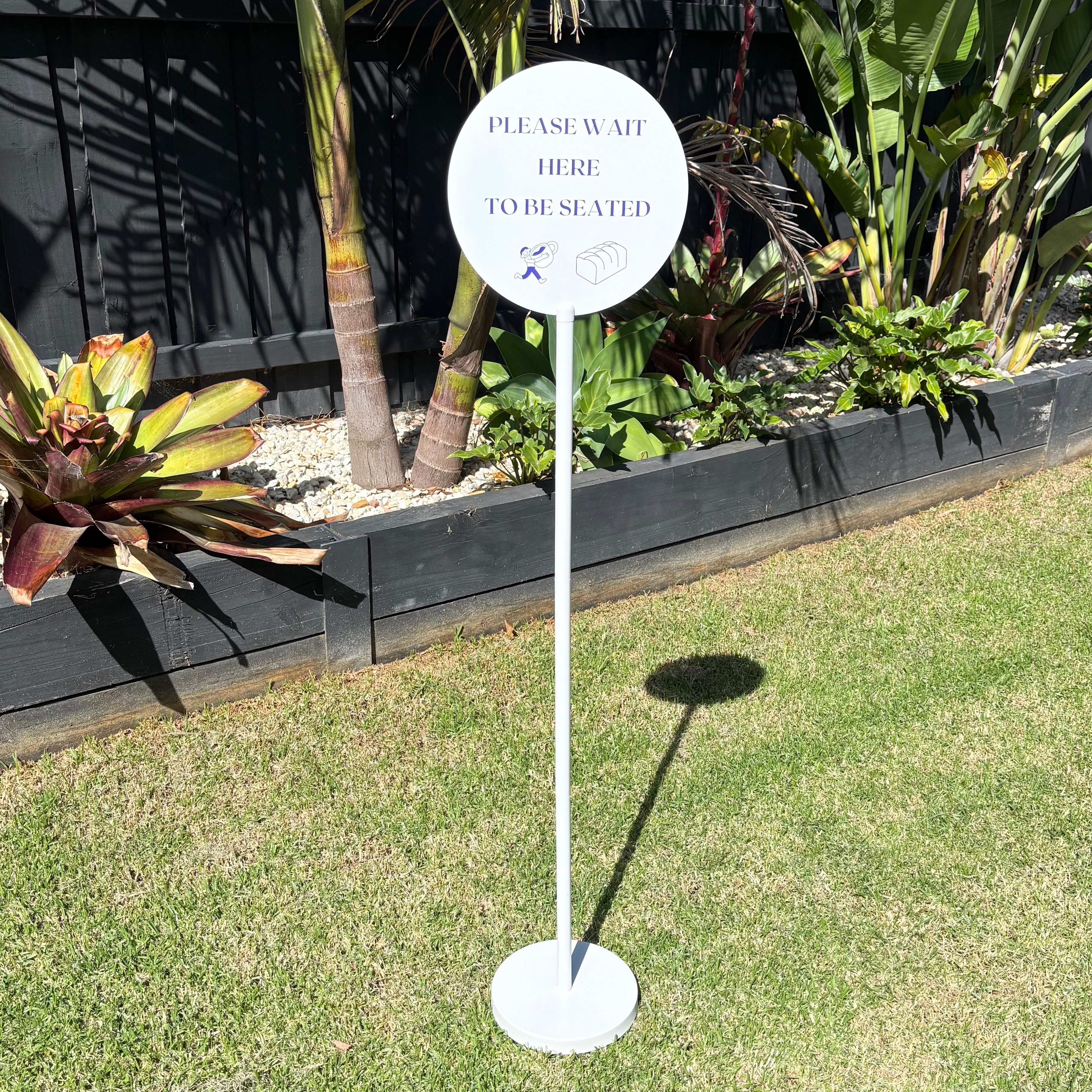 Round freestanding queue sign with stand, “please wait here to be seated” business sign, outdoor hospitality signage Australia, custom acrylic round sign with pole base, restaurant waiting area sign, modern minimal outdoor display sign for cafes and venues
