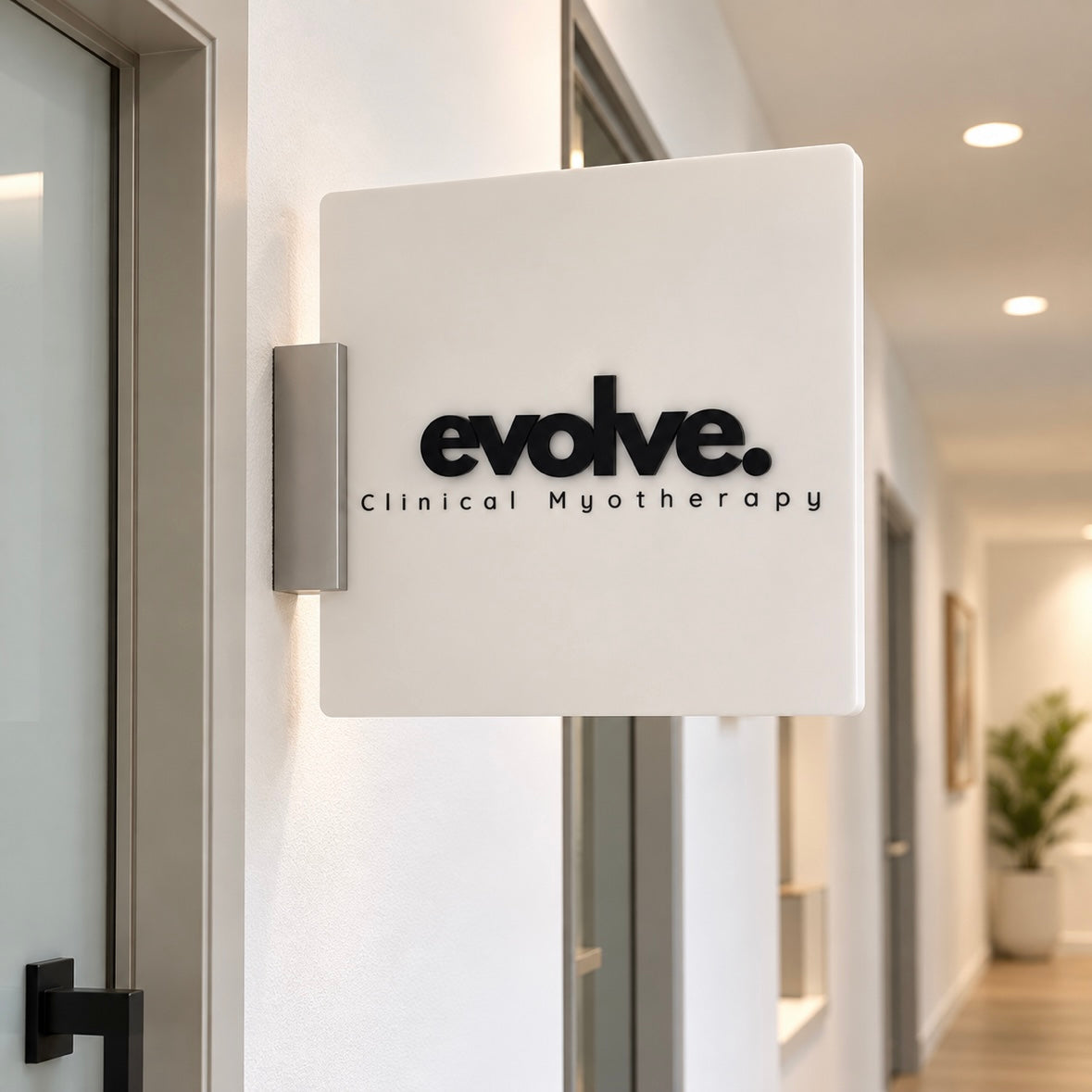 Custom white acrylic blade sign for Evolve Clinical Myotherapy, mounted beside a clinic door in a modern hallway.
