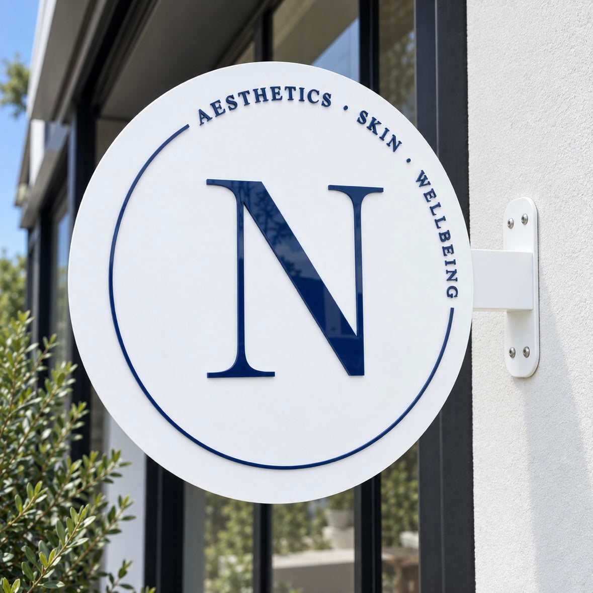 Custom round blade sign with navy 3D acrylic lettering for an aesthetics, skin and wellbeing clinic, mounted outside a modern business.