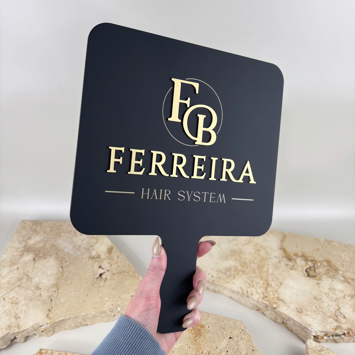 Custom branded handheld mirror with black acrylic and gold logo detailing, personalised for Ferreira Hair System.