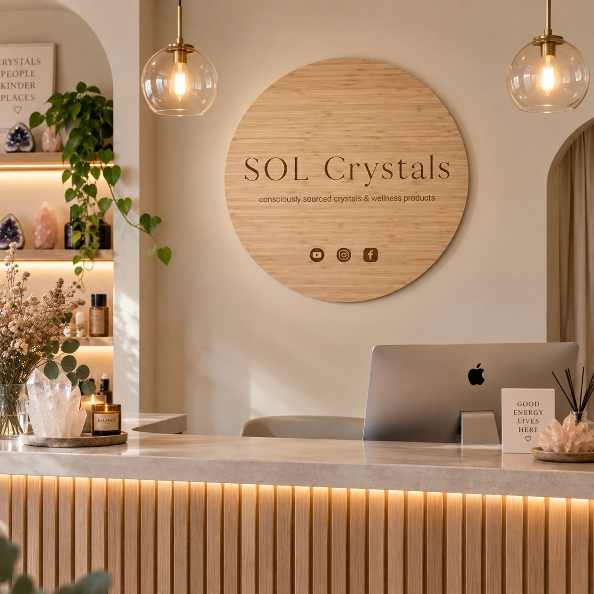 Custom round bamboo business sign for SOL Crystals with engraved logo and social media icons, mounted behind a modern crystal and wellness store reception desk.