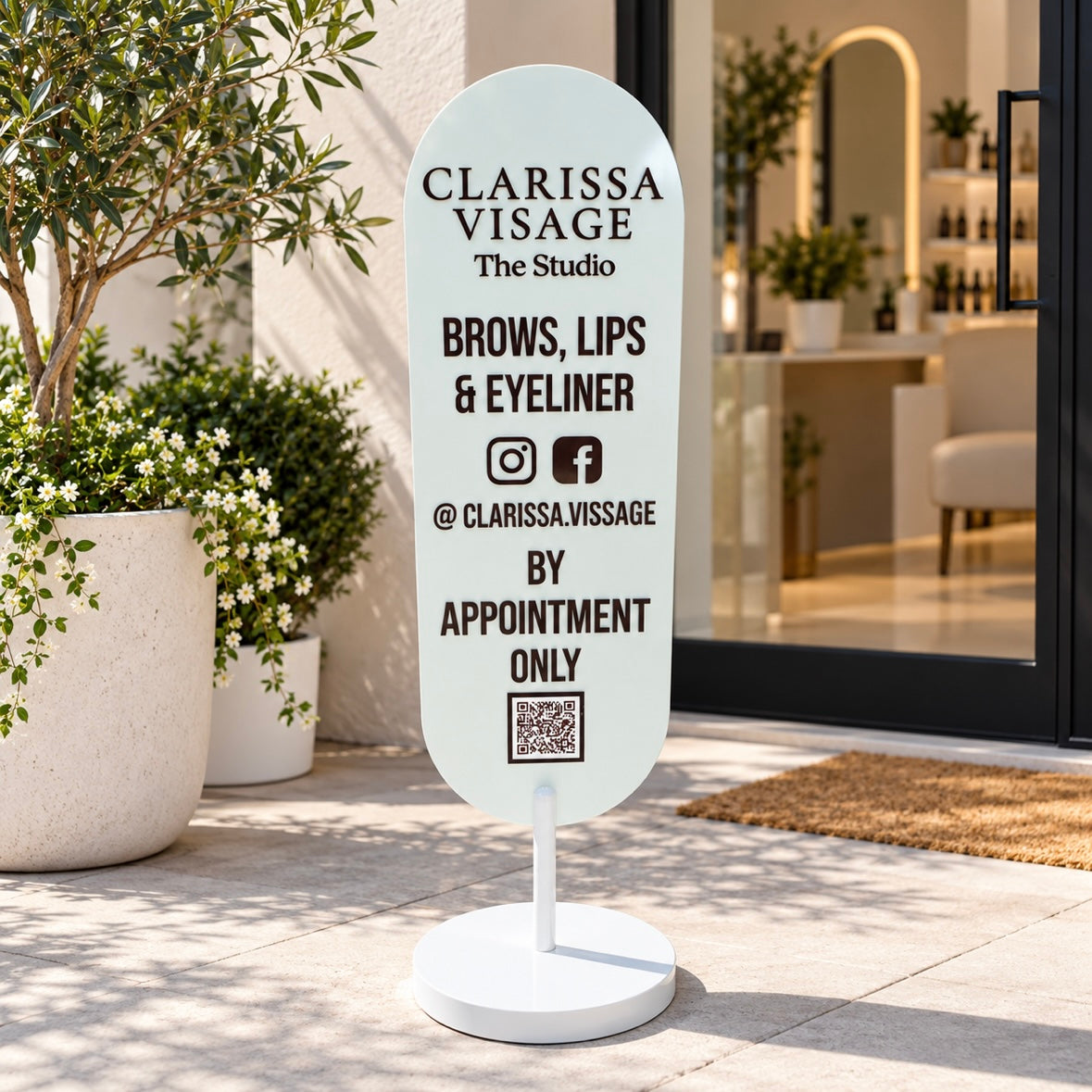 Custom freestanding oval business sign with raised acrylic lettering, social media icons and QR code displayed outside a modern beauty studio.