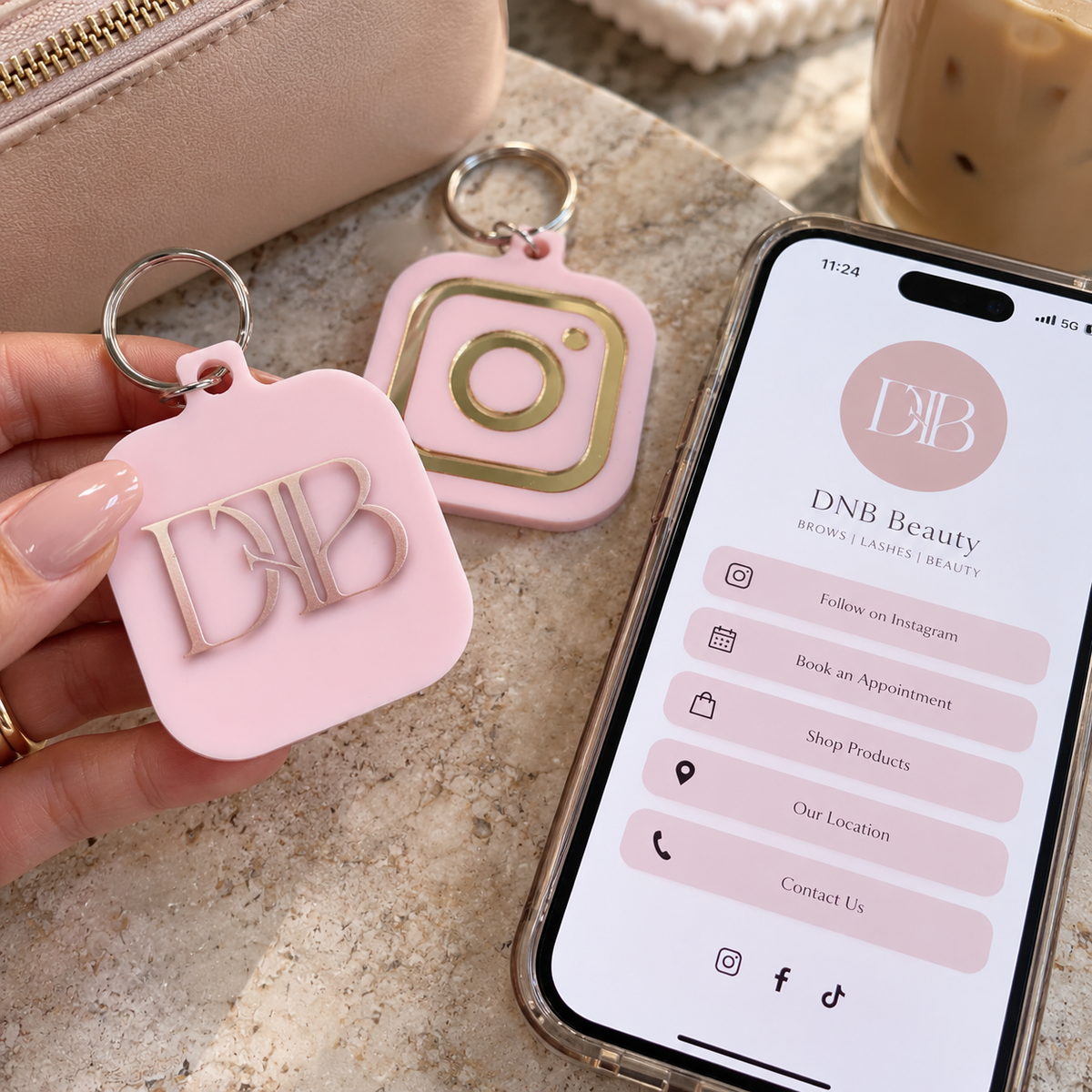 Custom pink acrylic NFC keychain with raised mirror logo and Instagram icon, shown beside a smartphone displaying a business profile.