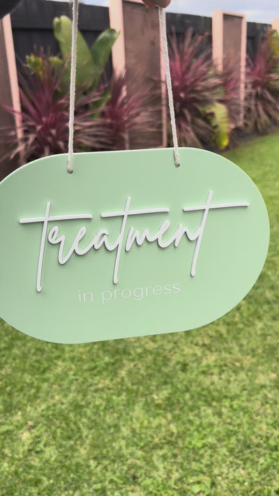 Mint green treatment in progress salon door sign shown outdoors with hanging cord. Video