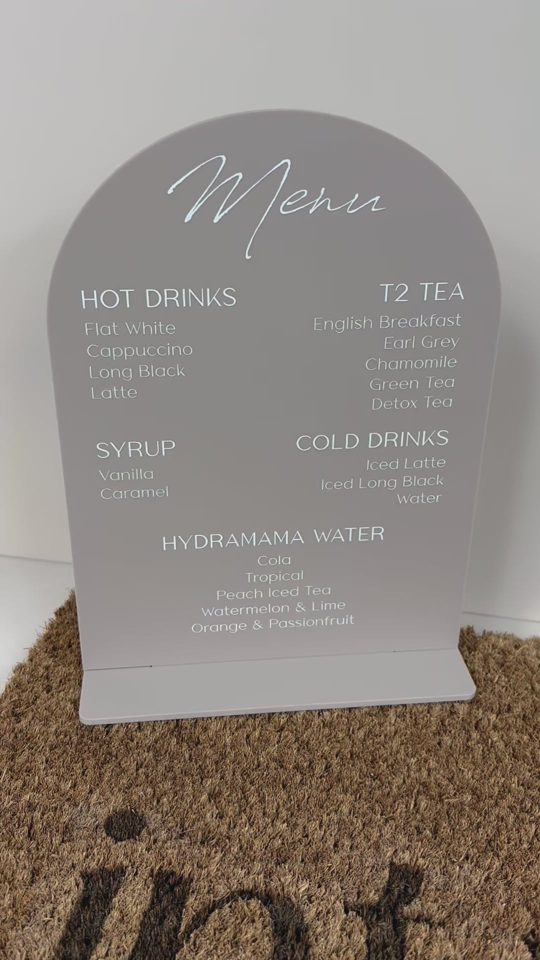Clear acrylic coffee shop menu sign with white text on cork mat