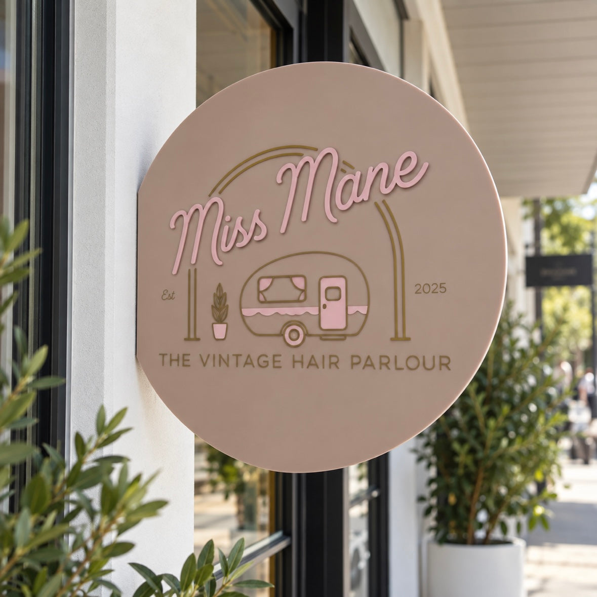Custom round blade sign for Miss Mane Vintage Hair Parlour with pink and gold acrylic details, mounted outside a modern hair salon.