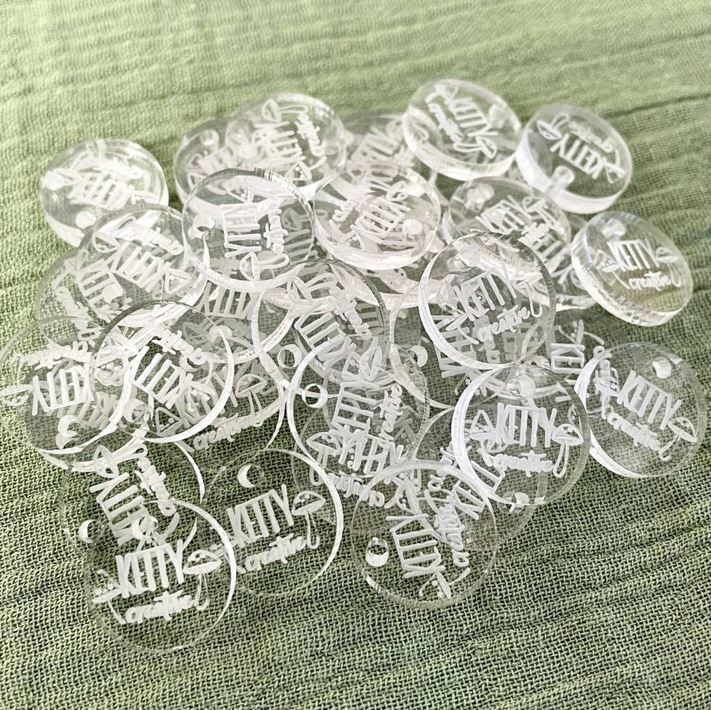 Clear round acrylic tags engraved with branding for handmade items
