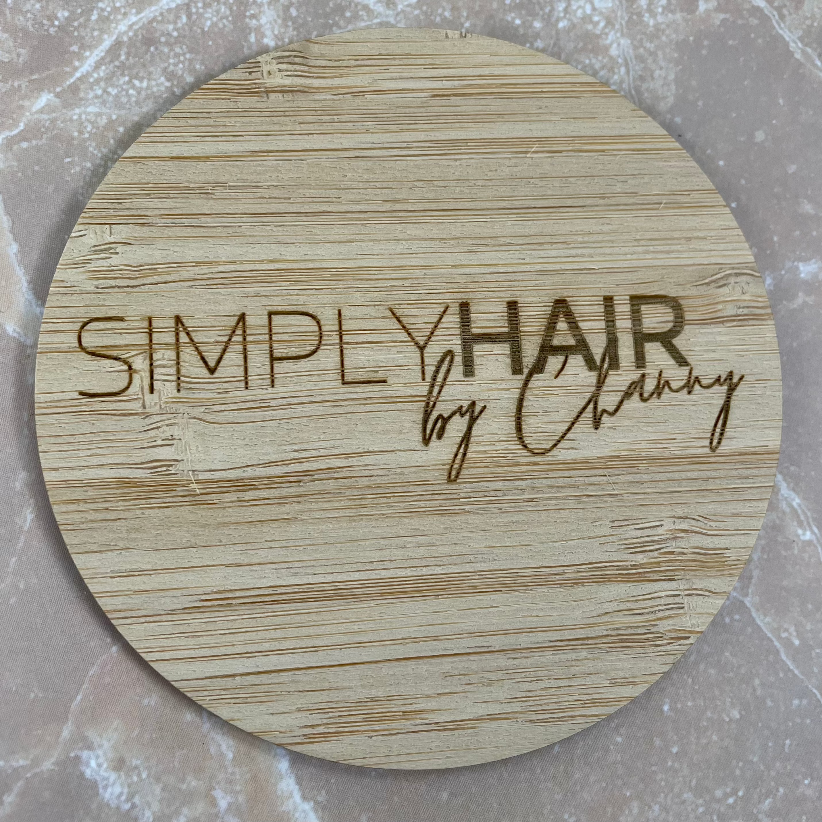 Custom engraved bamboo logo disc for salon branding and product styling photography