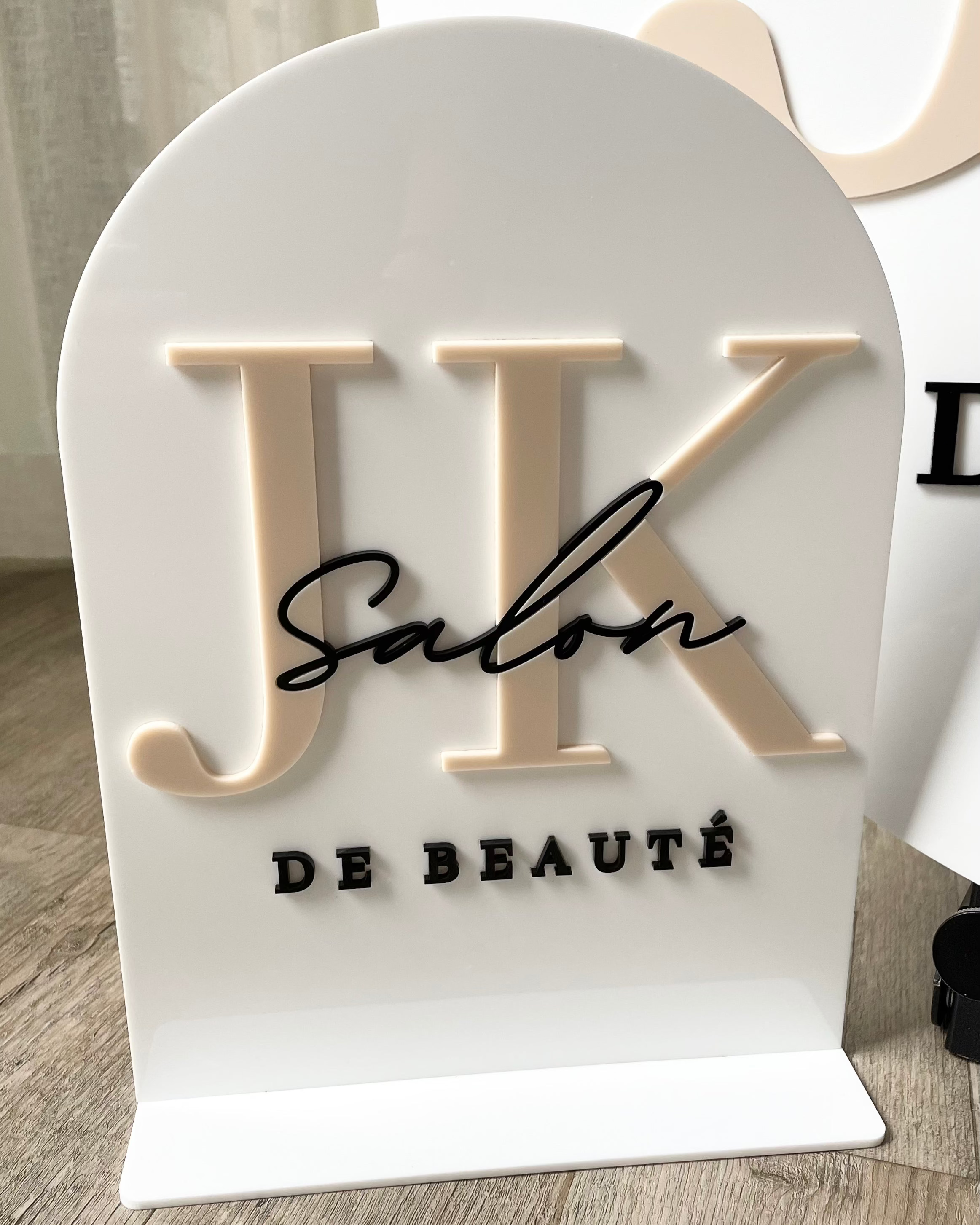 White acrylic sign with raised black logo and business name