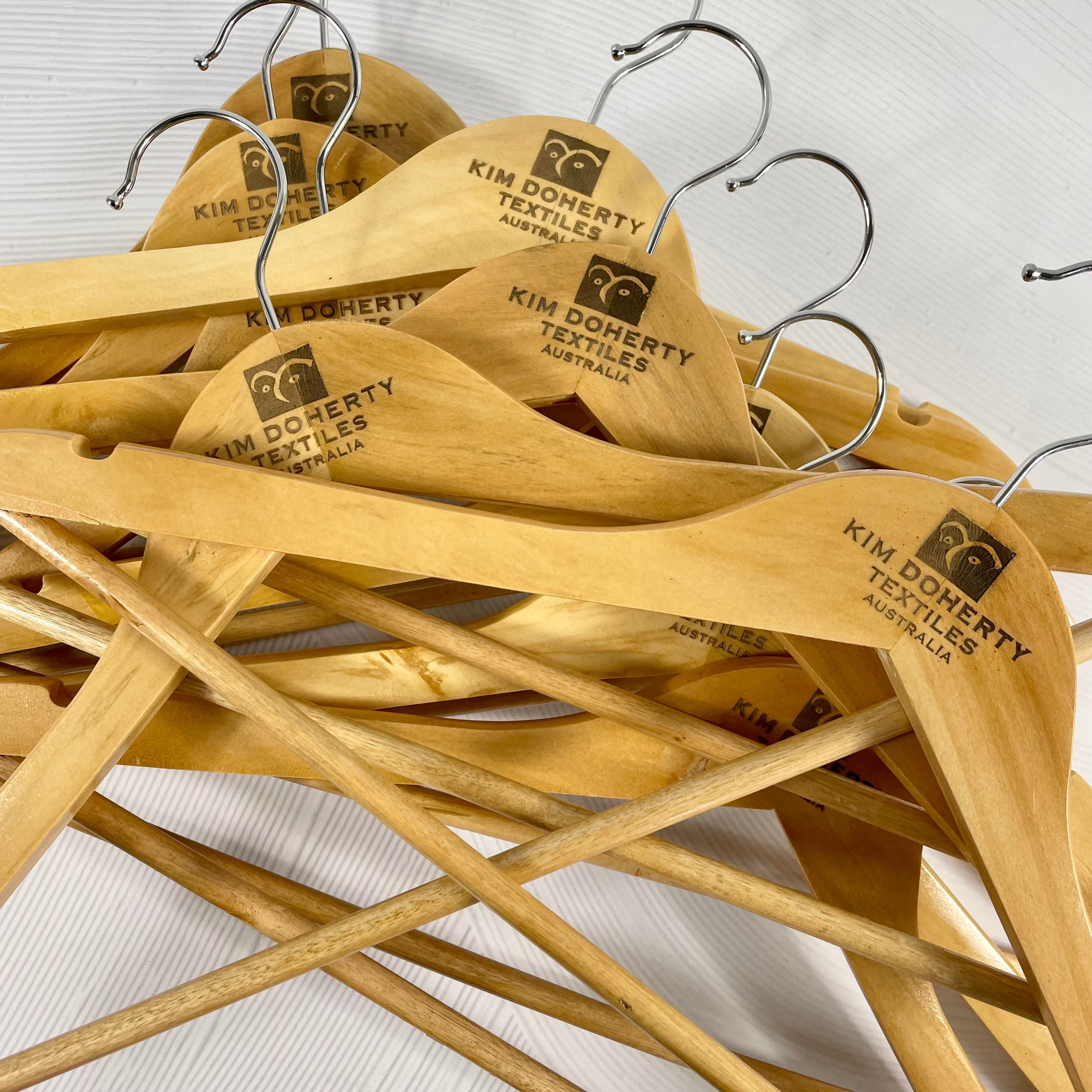Stack of custom logo coat hangers ready for salon or retail use