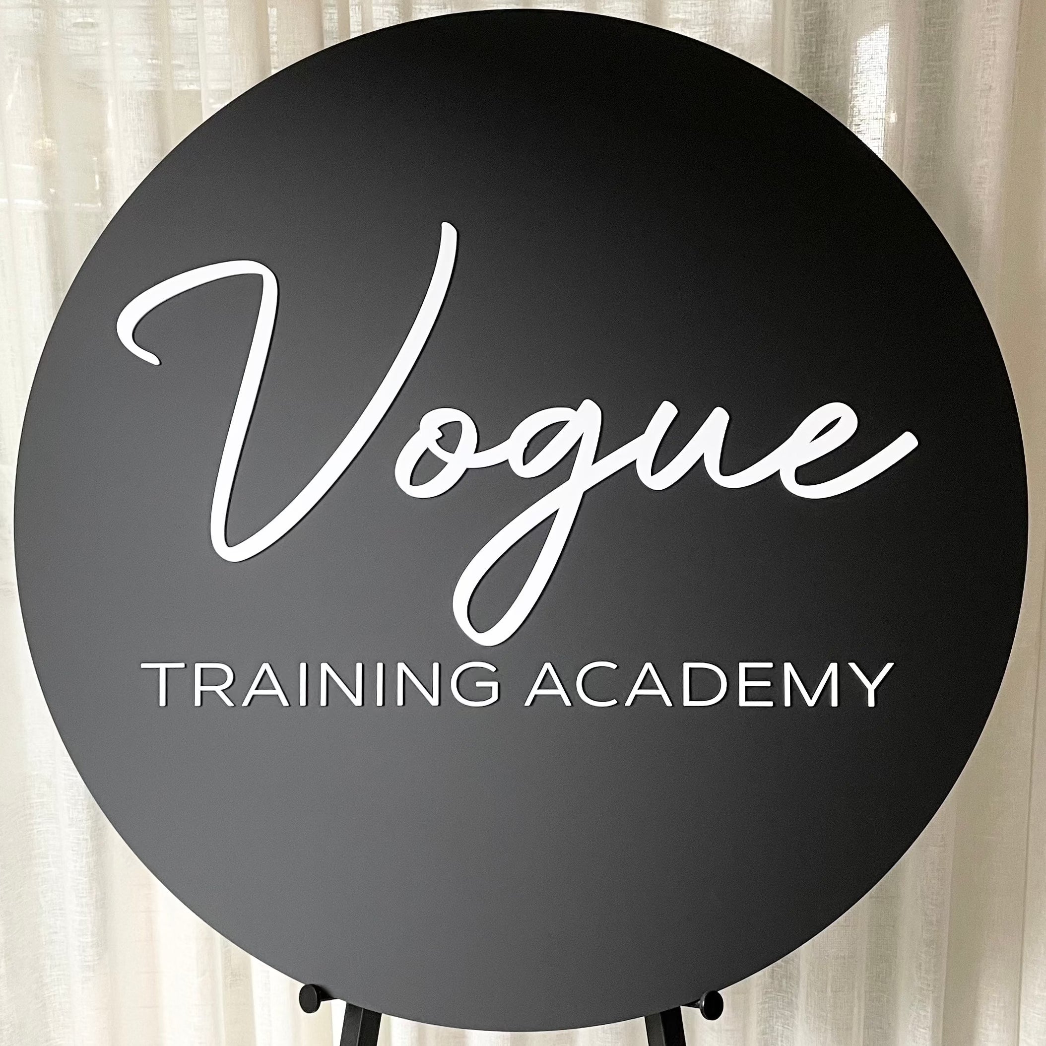 matte black round acrylic sign with vogue training academy text